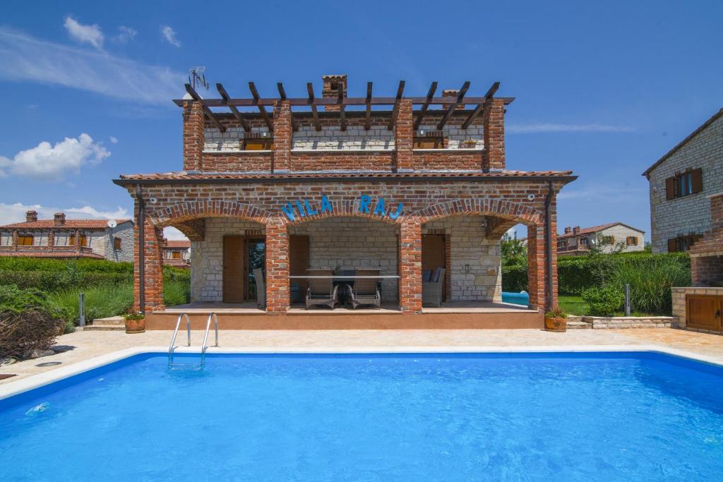 a villa with a swimming pool and a building at Vila Raj Juršići in Butkovići