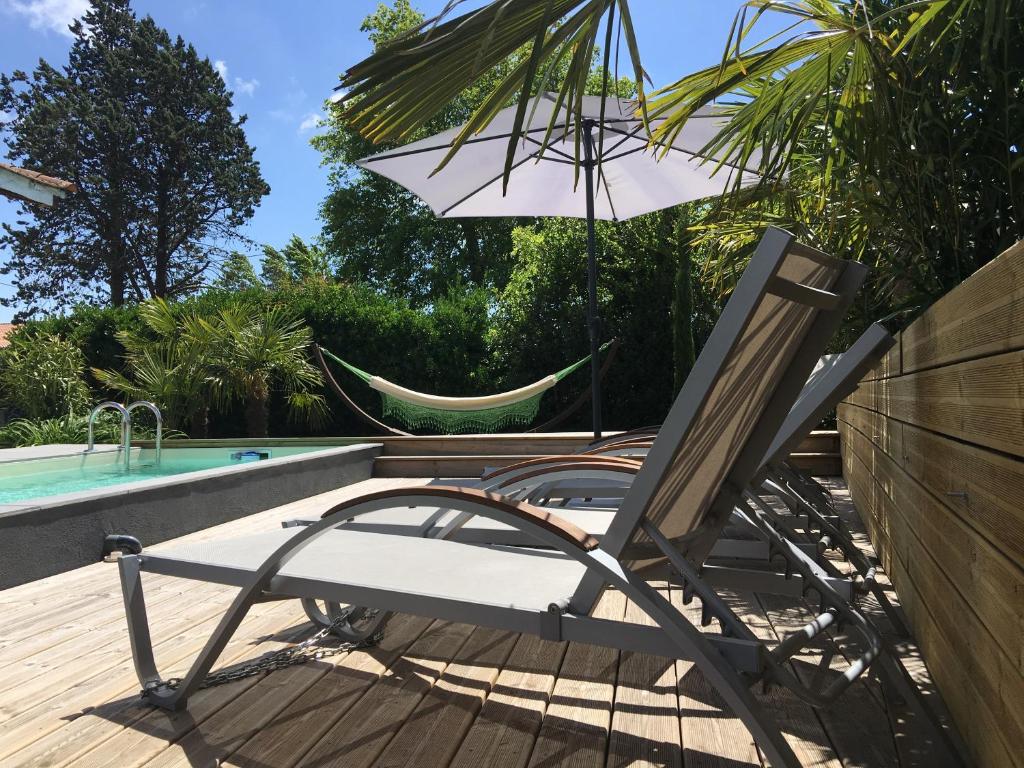 uma rede de descanso e uma cadeira junto a uma piscina em La ravissante ferretcapienne em Lège-Cap-Ferret