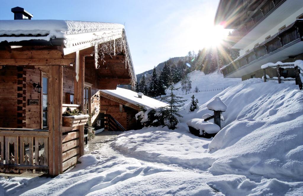 a house covered in snow with the sun behind it at Bauerndörfl Hüttschlag in Hüttschlag