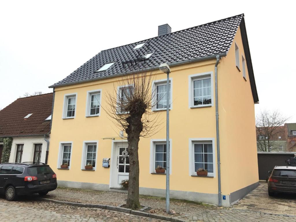 une maison jaune avec un toit noir dans l'établissement Gäste-Apartment "Carpe Diem", à Osterburg