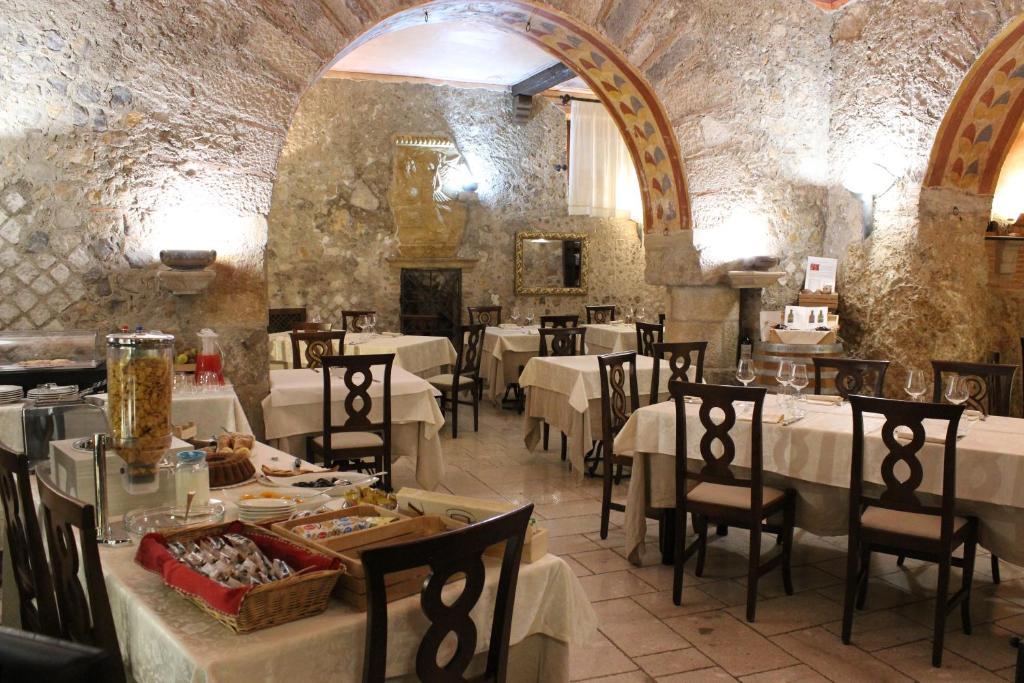restauracja z białymi stołami i krzesłami oraz kominkiem w obiekcie Villa Cosilinum w mieście Padula