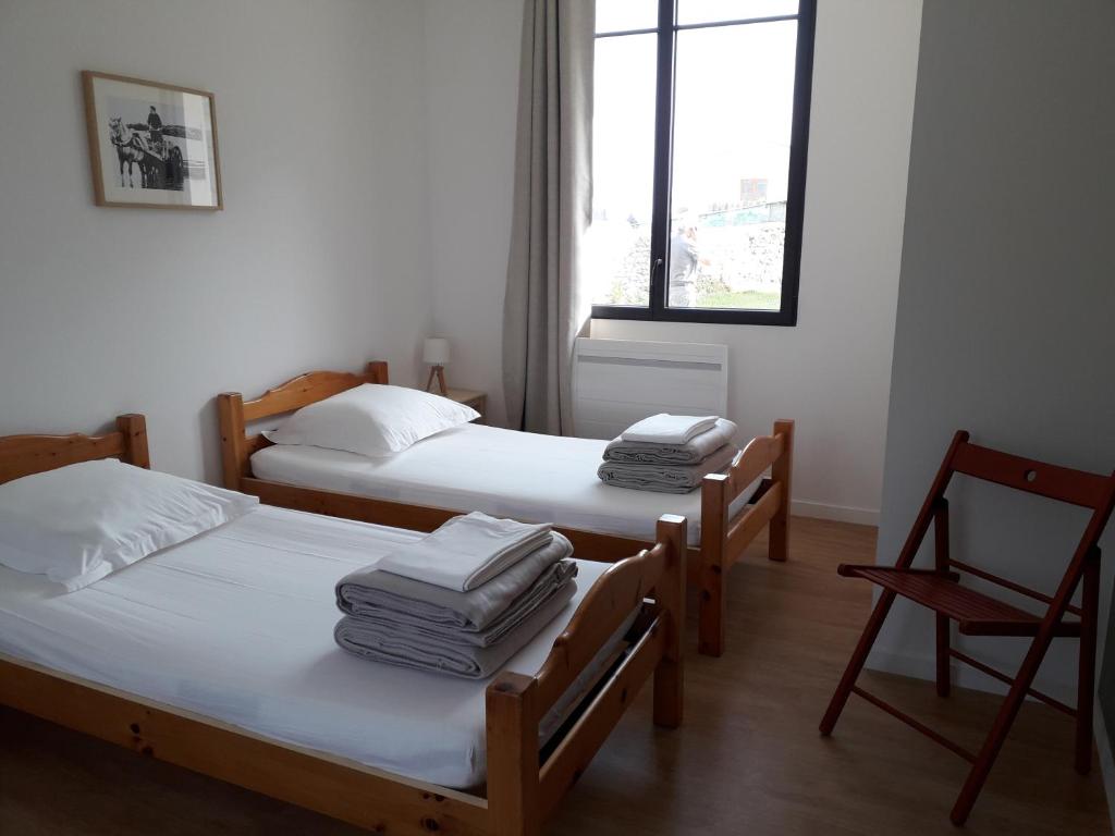 a room with three beds and a chair and a window at Gîte Les Pingouins du Phare in Plouguerneau