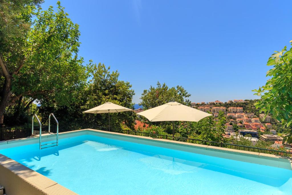 a swimming pool with two umbrellas and a view at Villa Tranquillity XII in Dubrovnik