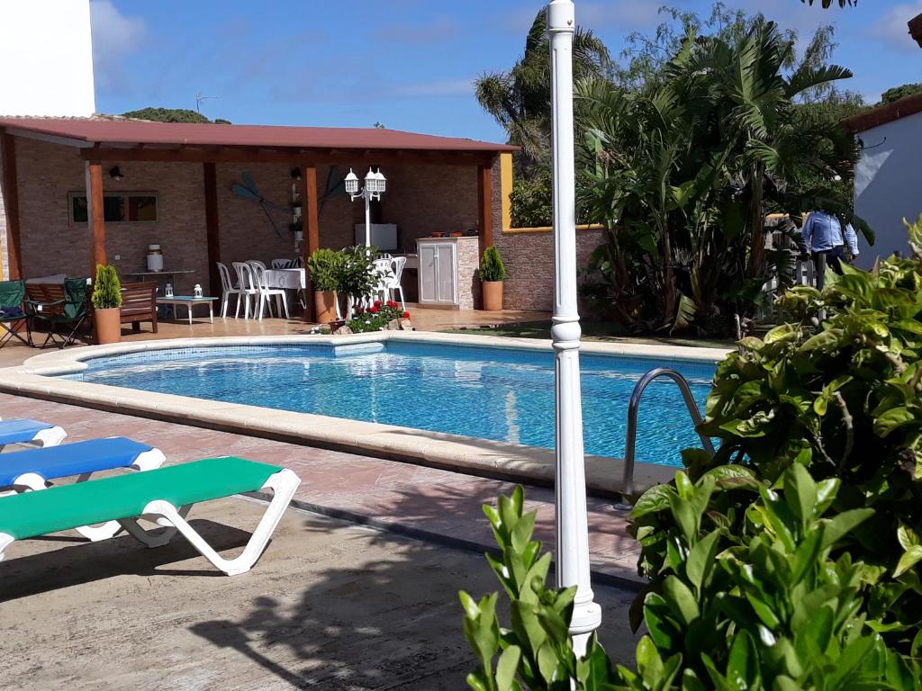 una piscina con 2 sillas y una casa en Chalet la Huerta con piscina y Wifi en Conil de la Frontera