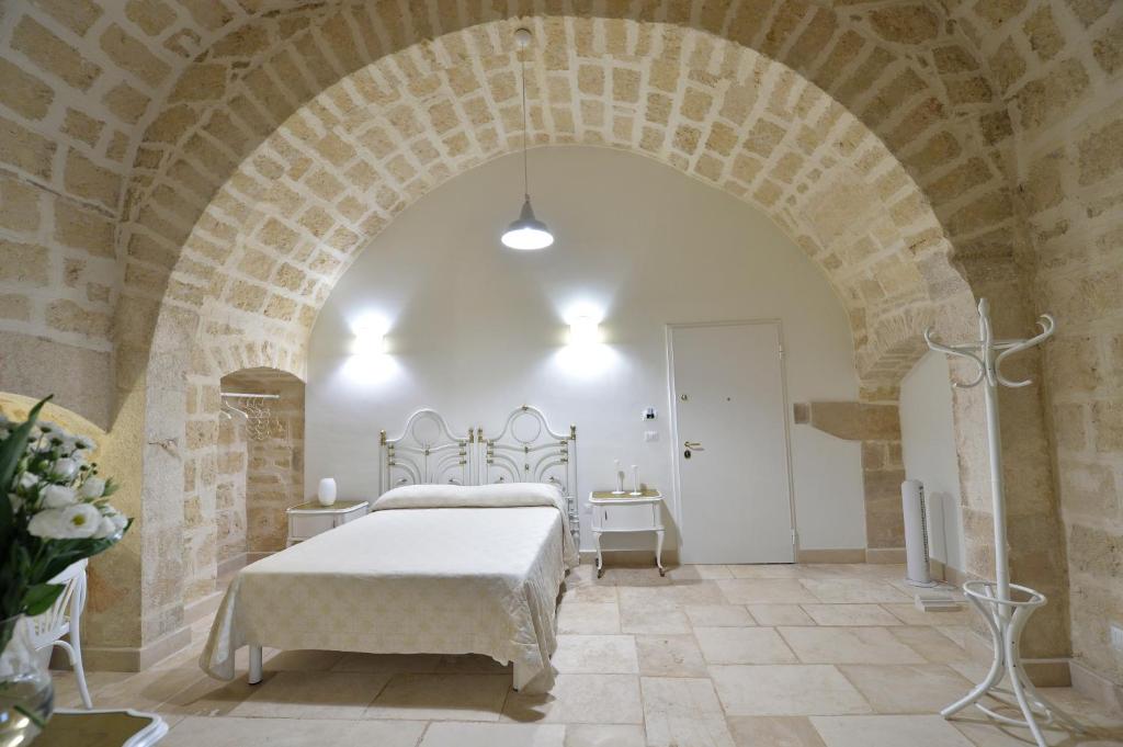 una camera con un letto bianco su un muro di mattoni di Le Stanze di Filippo Tandoi a Corato