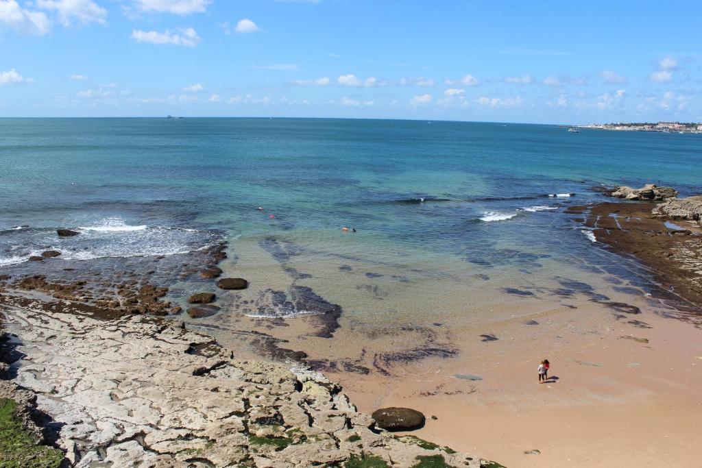 a person standing on a beach near the ocean at Casa da Azarujinha in Estoril