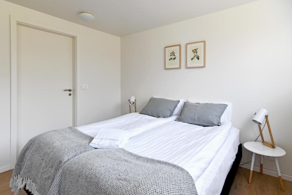 a white bedroom with a large bed and a table at Natura Apartments in Laugar