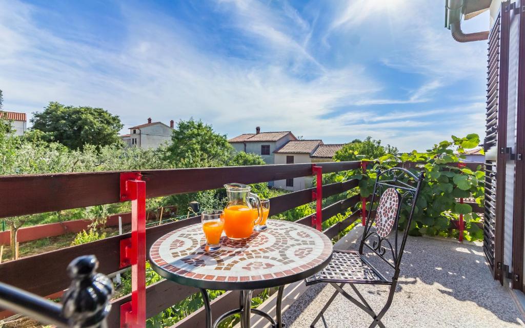 a table with two glasses of orange juice on a balcony at Three-Bedroom Apartment Meden in Pomer