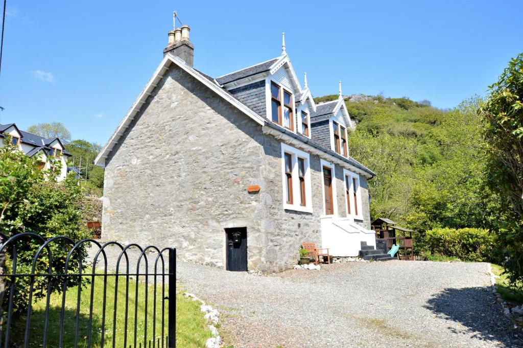 an old stone house with a gate in front of it at Aldersyde in Tighnabruaich