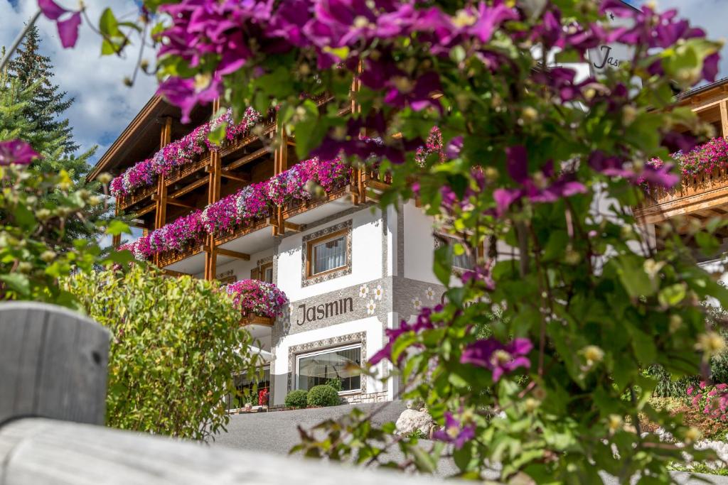 a building with purple flowers in front of it at Garni Jasmin in San Cassiano