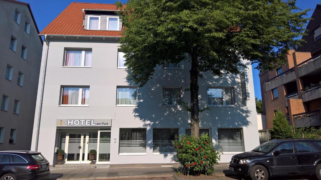 ein weißes Gebäude mit einem Baum davor in der Unterkunft Hotel am Park in Braunschweig