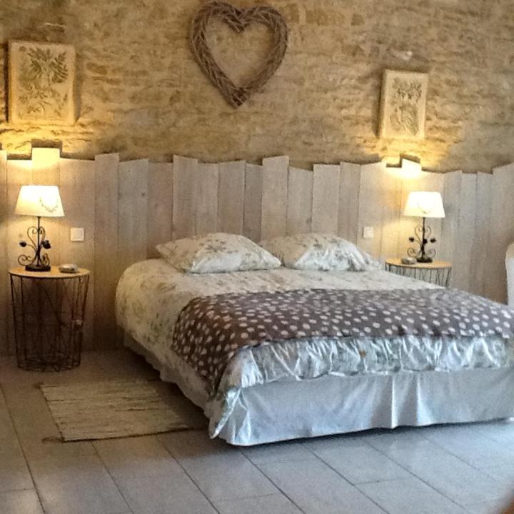 une chambre avec un lit avec un cœur sur le mur dans l'établissement Le Champêtre, à Bazoges-en-Pareds