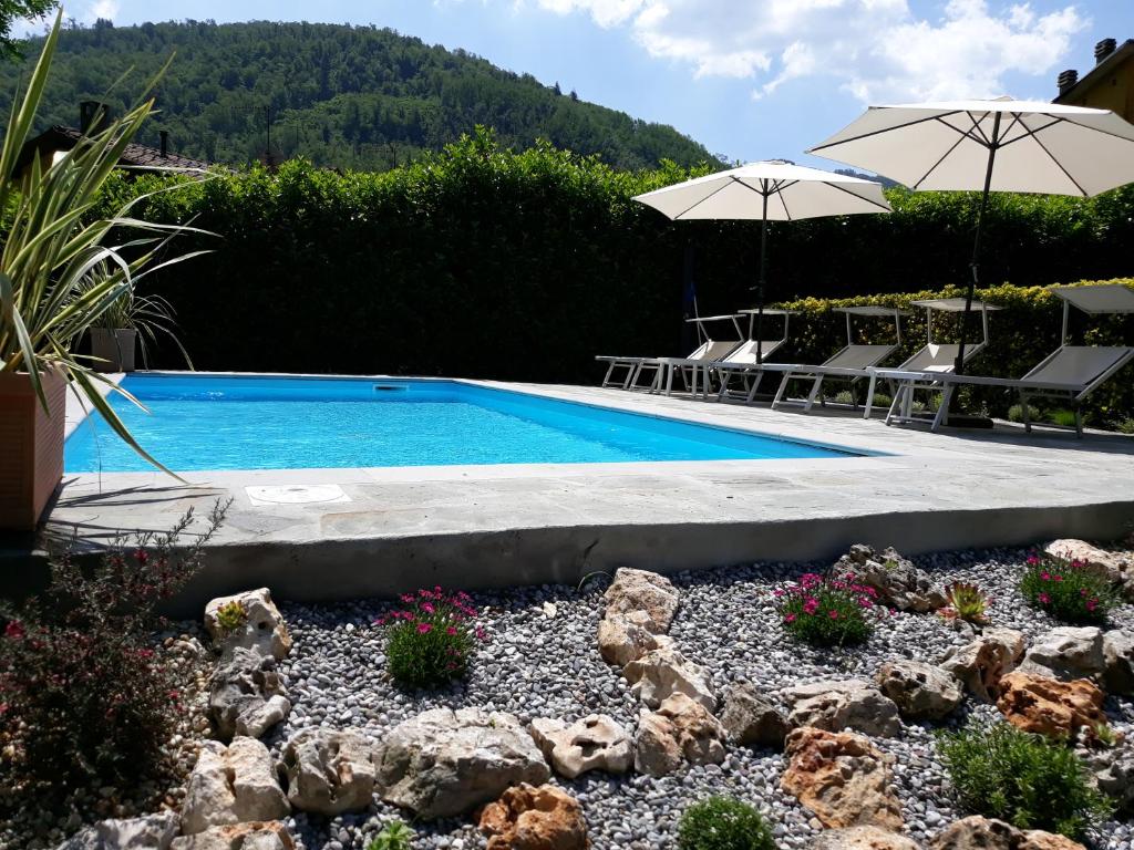 einen Pool mit Stühlen und Sonnenschirmen im Hof in der Unterkunft Casa Webb in Bagni di Lucca