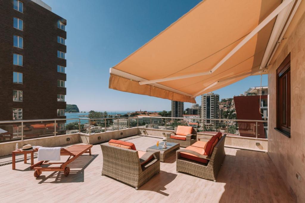 a patio with chairs and tables and a large umbrella at City Apartments in Budva