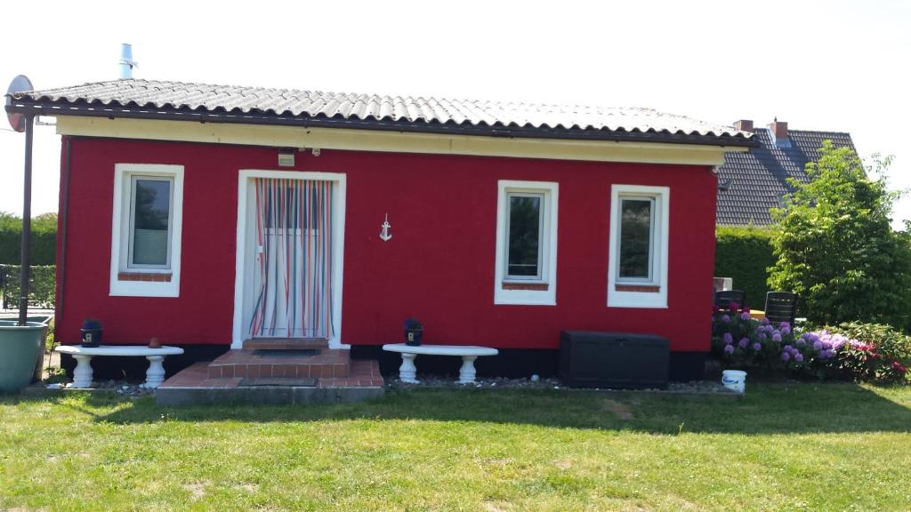 a red house with two picnic tables in front of it at Ferienhaus Storchenweg in Mahlzow