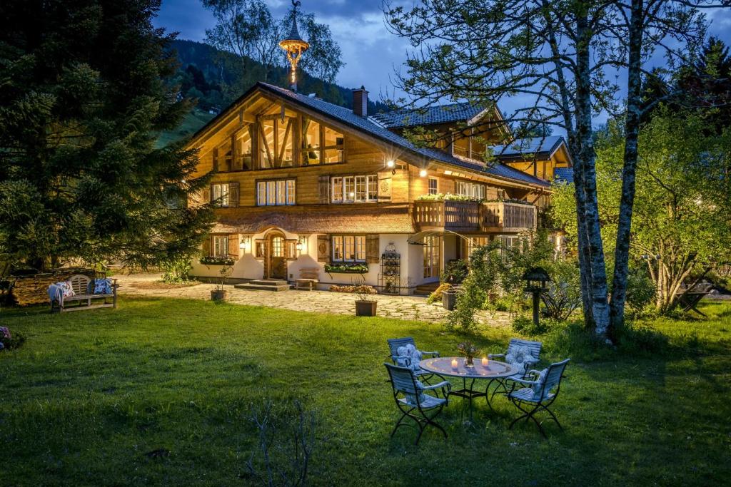 a large wooden house with a table in the yard at Das Talgut in Ofterschwang