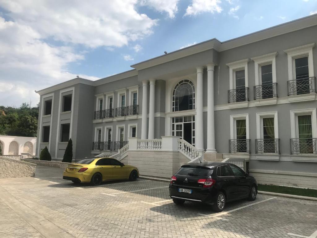 dos coches estacionados frente a un edificio en Jurgen Resort, en Tirana