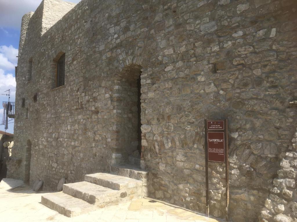 una pared de piedra con escaleras y un cartel al lado en La Portella en Oppido Lucano