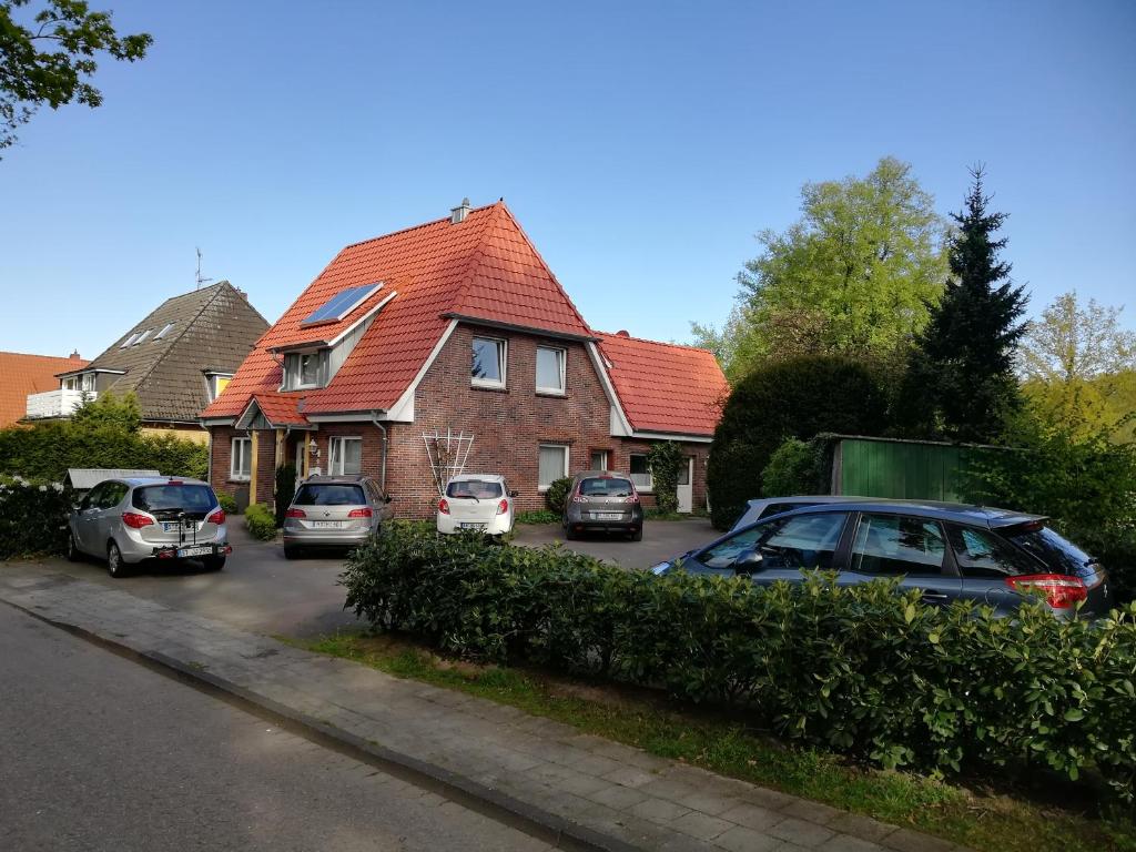 une maison avec des voitures garées dans un parking dans l'établissement Pension-Marion, à Bad Zwischenahn