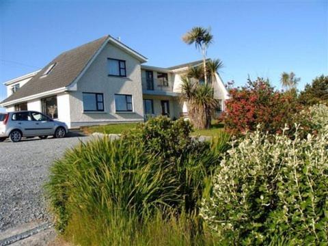 a house with a car parked in a driveway at DeCourcey's Hazelbrook Farmhouse B&B in Cleggan