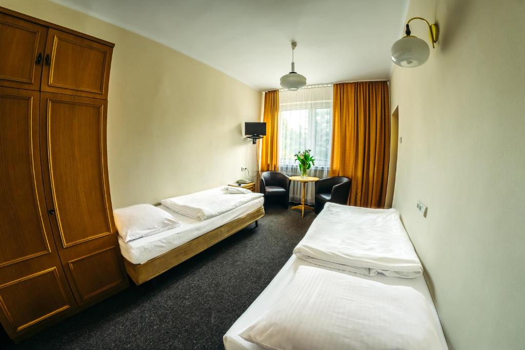 una habitación de hotel con 2 camas y una silla en Ośrodek Szkoleniowo-Wypoczynkowy "Stodoły", en Rybnik