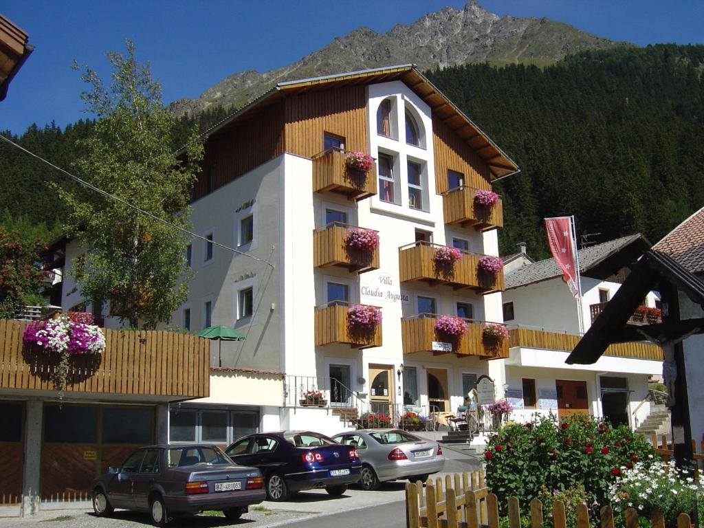 a building with balconies and cars parked in a parking lot at Pension Villa Claudia Augusta in Resia
