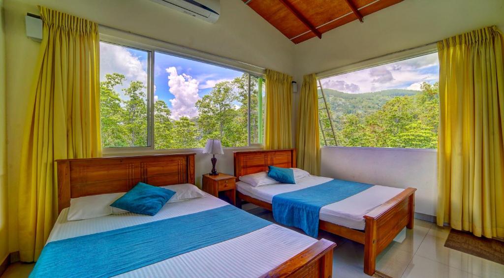 two beds in a room with a large window at Hanthana Holiday Rooms in Kandy