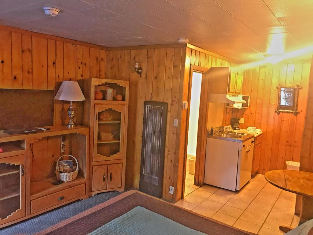 a kitchen with wooden walls and a refrigerator and a table at Caboose Motel & Gift Shop in Durango