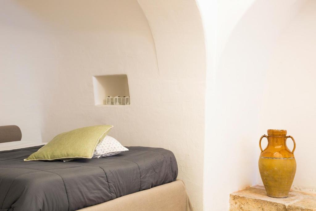 1 dormitorio con 1 cama y un jarrón sobre una mesa en Il Trullo del viaggiatore, en Alberobello