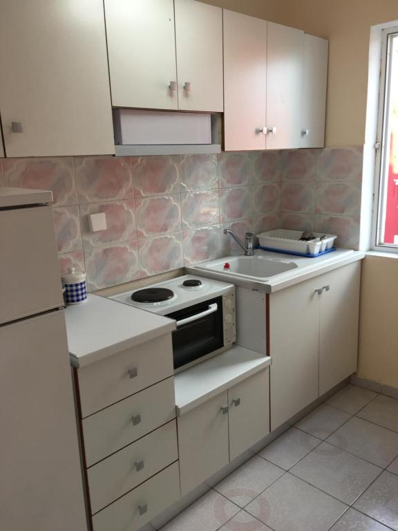 eine Küche mit weißen Schränken, einem Herd und einer Spüle in der Unterkunft City Center Apartment in Himarë