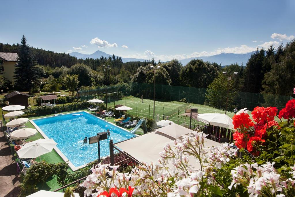 une piscine extérieure avec des parasols et des fleurs dans l'établissement Hotel Scoiattolo, à Baselga di Pinè