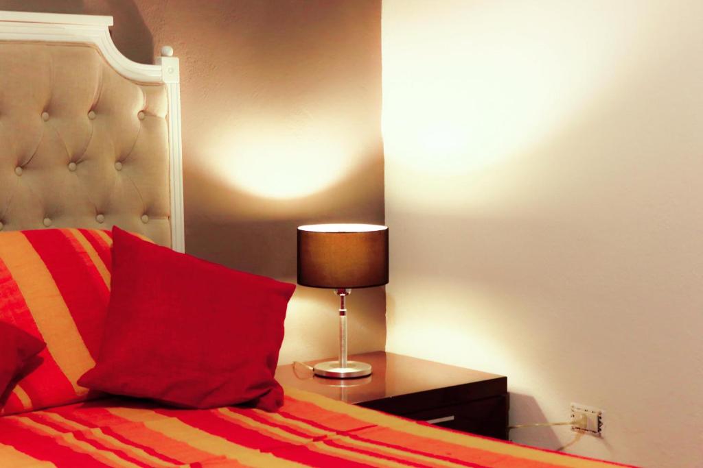 ジャッレにあるCasa Vacanze Stellaのベッド(赤い枕、テーブルの上のランプ付)