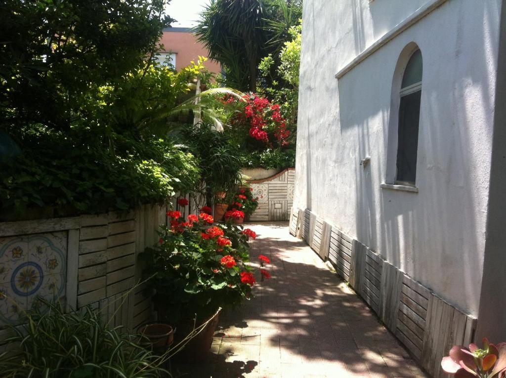 an alley with red flowers and a building at Piccolo Tirreno Hotel Residence in Procida