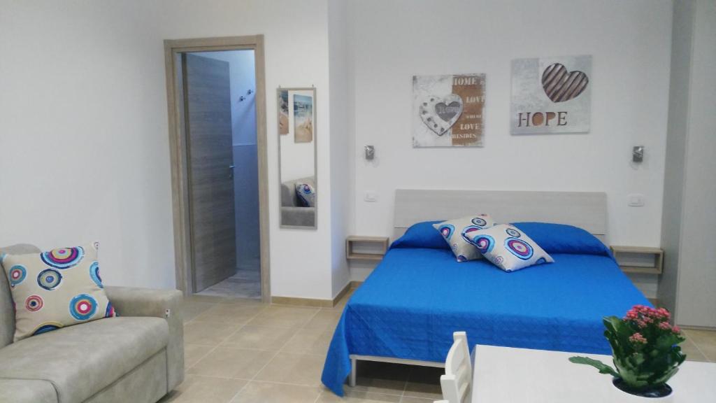 een slaapkamer met een blauw bed en een bank bij Aria di Casa in Porto Cesareo