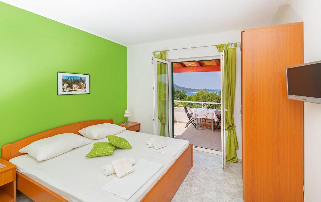 a bedroom with a bed and a television and a balcony at Sunny House Free Parking in Trsteno