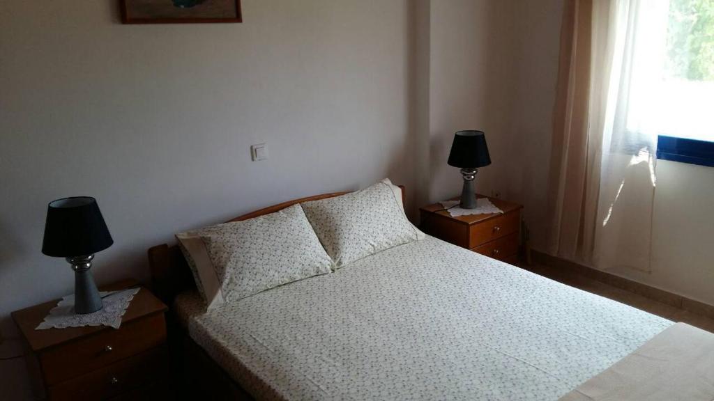 a bedroom with a bed and two lamps on night stands at Vlachogiannis EL Estate in Skala Rachoniou