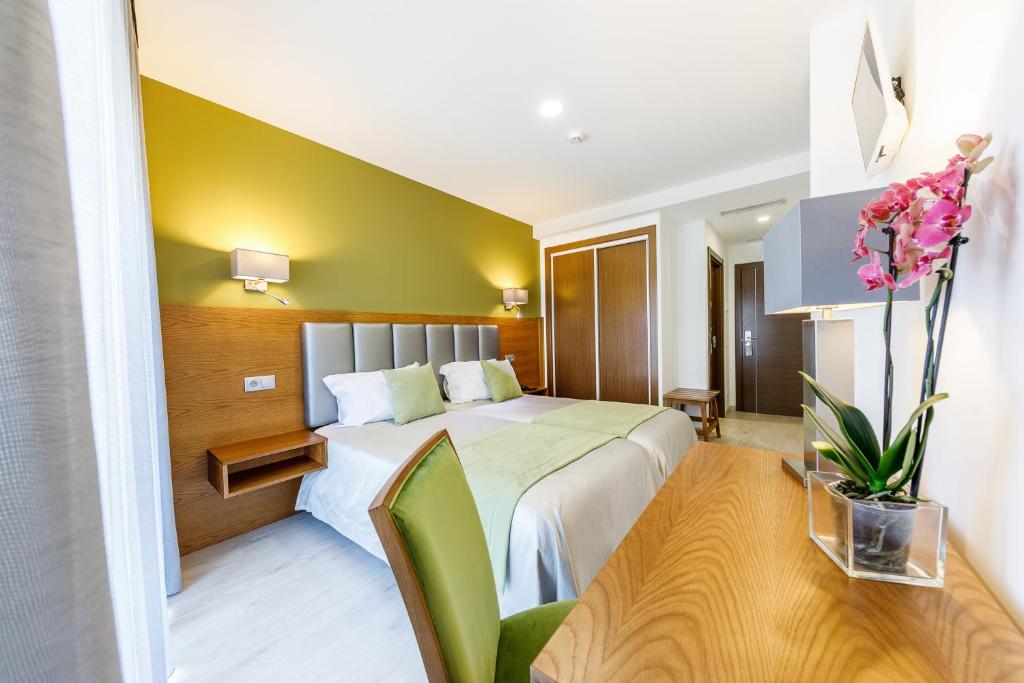 um quarto de hotel com uma cama e uma parede verde em Hotel Santo António de Pádua em Fátima