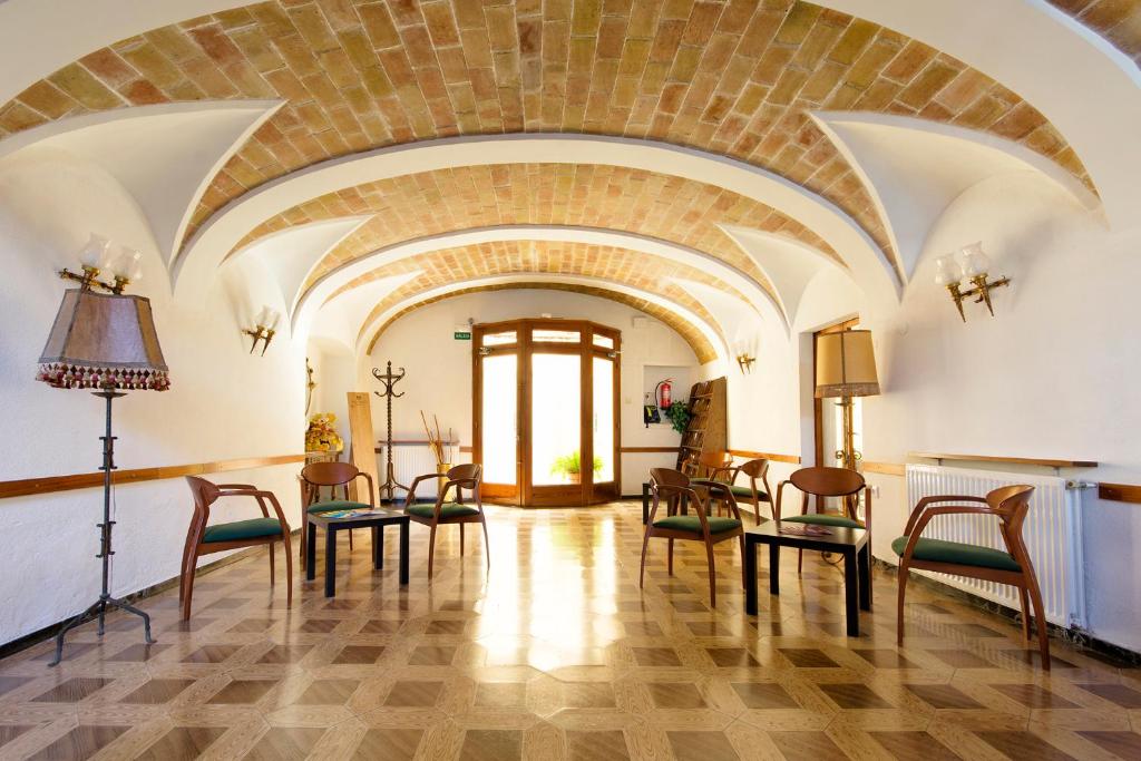 Großes Zimmer mit Stühlen und Ziegeldecke in der Unterkunft Hostal Fabrellas in Caldes de Malavella
