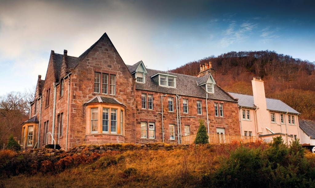 un gran edificio de ladrillo en la cima de una colina en Loch Maree Hotel, en Talladale