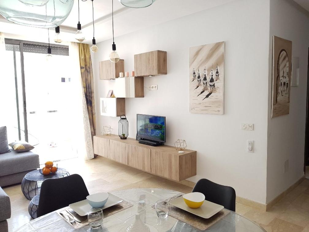 un salon avec une table en verre et une télévision dans l'établissement residence agadir bay founty, à Agadir