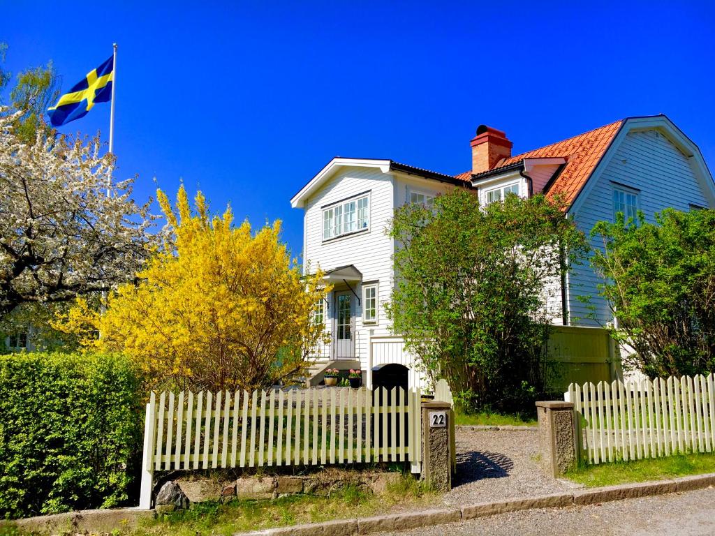a white house with a white picket fence and a flag at Family villa near sea and Stockholm city in Stockholm