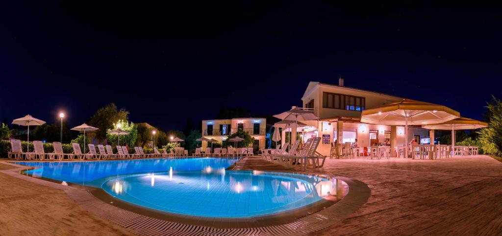 a swimming pool with chairs and umbrellas at night at Yianetta Hotel Apartments in Kavos