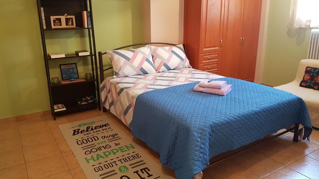 een slaapkamer met een bed met een blauwe deken bij Cozy Loft in Mesolongion