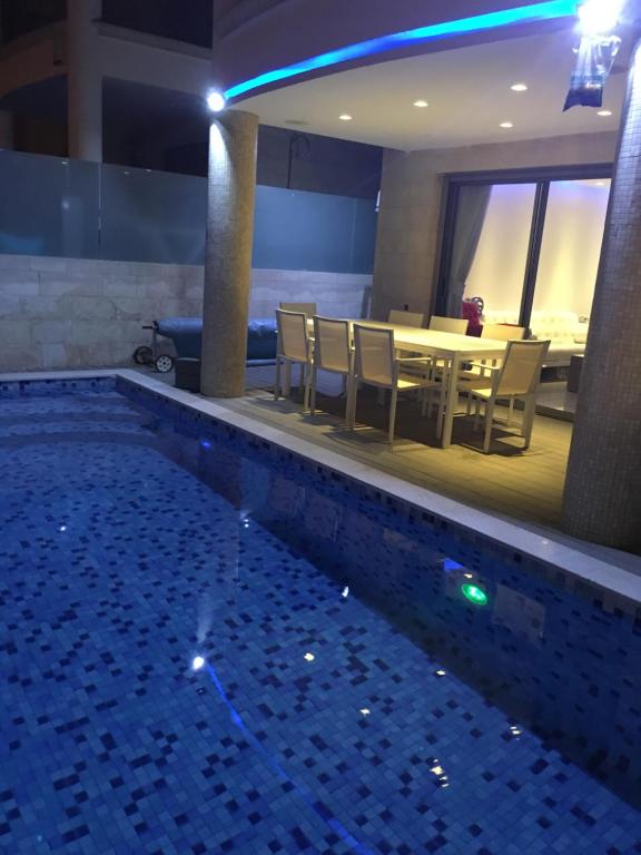 a pool in a hotel with a table and chairs at Aquarelle in Eilat