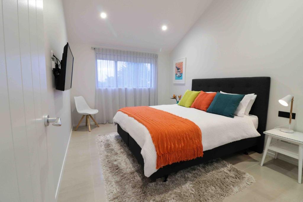 1 dormitorio con 1 cama grande y almohadas coloridas en Halfmoon Bay Apartment en Auckland