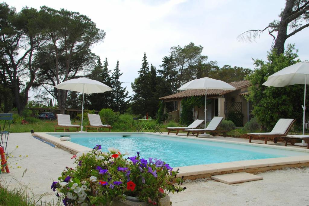ein Pool mit Sonnenschirmen und Blumen im Hof in der Unterkunft La Coudoulière in Saint-Rémy-de-Provence