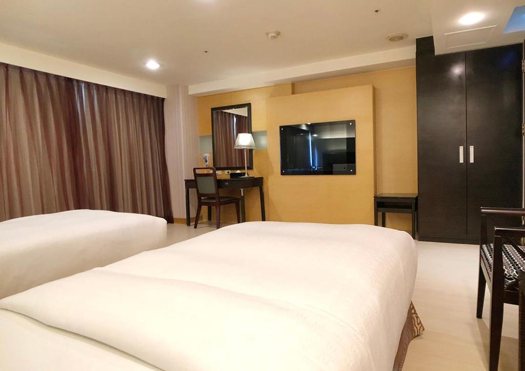 a hotel room with two beds and a table at Shihzuwan Hotel – Kaohsiung Station in Kaohsiung