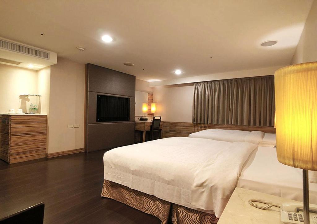 a bedroom with a large bed and a television at Shihzuwan Hotel – Kaohsiung Station in Kaohsiung