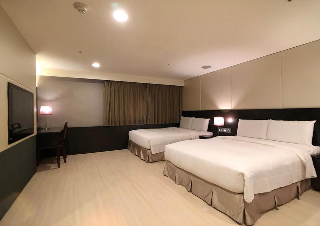 a hotel room with two beds and a flat screen tv at Shihzuwan Hotel – Kaohsiung Station in Kaohsiung