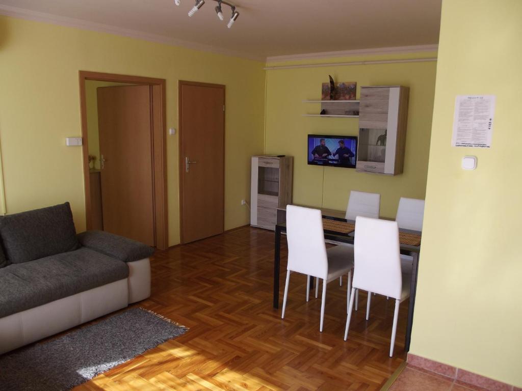 uma sala de estar com um sofá, uma mesa e cadeiras em Pillangó Apartman em Hajdúszoboszló